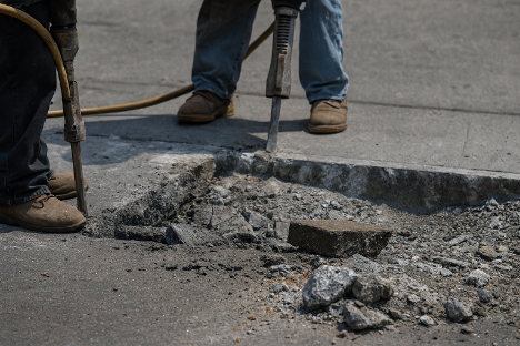 Sidewalk construction in New York City residential area disturbing soil near buildings
