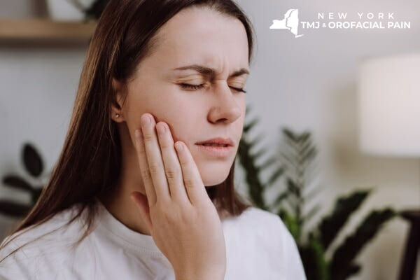 Woman holding her jaw due to TMJ pain and facial discomfort